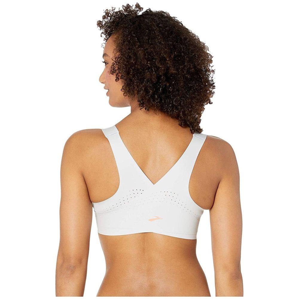 Woman wearing Brooks Dare Zip sports bra in ash gray, back view showing ventilation