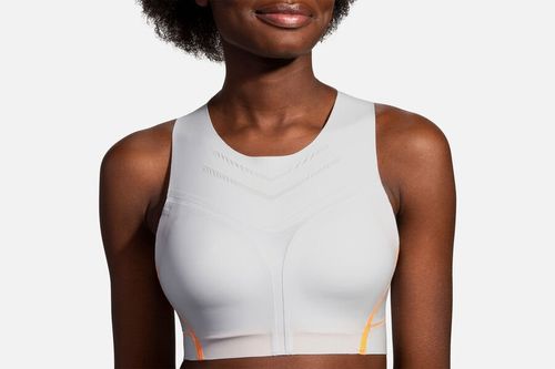 Woman wearing Brooks Dare High-Neck sports bra in ash gray with orange trim