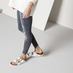 White Birkenstock Arizona sandals with two adjustable straps on model's feet