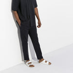 White Birkenstock Arizona sandals worn with black pants in studio setting