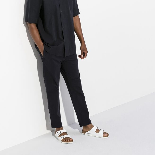 White Birkenstock Arizona sandals worn with black pants in studio setting