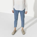 Person wearing taupe Birkenstock Boston clogs with jeans in studio setting