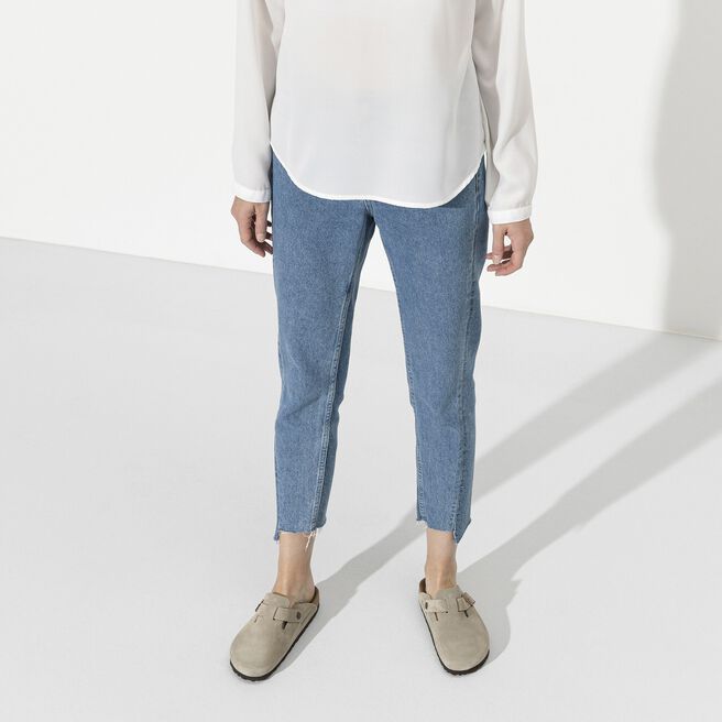 Person wearing taupe Birkenstock Boston clogs with jeans in studio setting