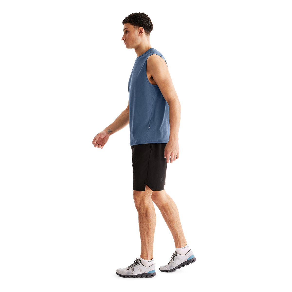 Man wearing black On Focus shorts with blue tank top in studio setting