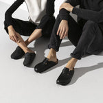 Two people wearing black Birkenstock Boston clogs in professional studio setting