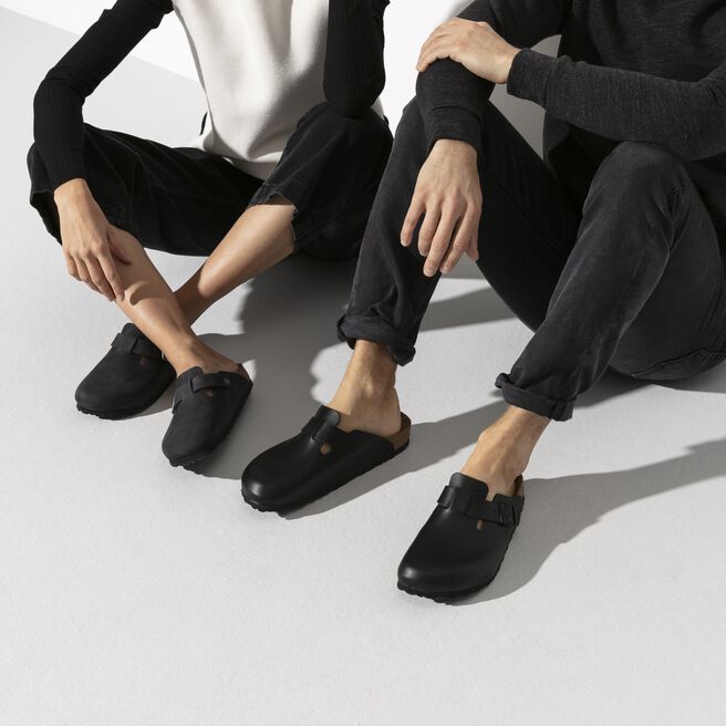 Two people wearing black Birkenstock Boston clogs in professional studio setting