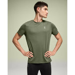 Man wearing olive green On Core-T athletic shirt in studio setting