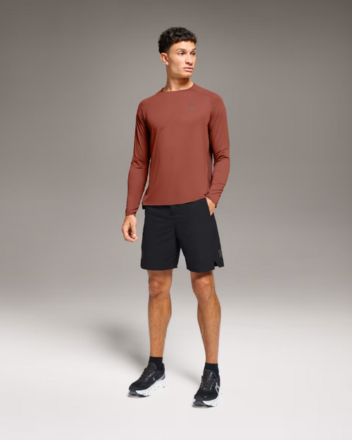 Man wearing black On Performance Hybrid Shorts with rust colored long sleeve shirt