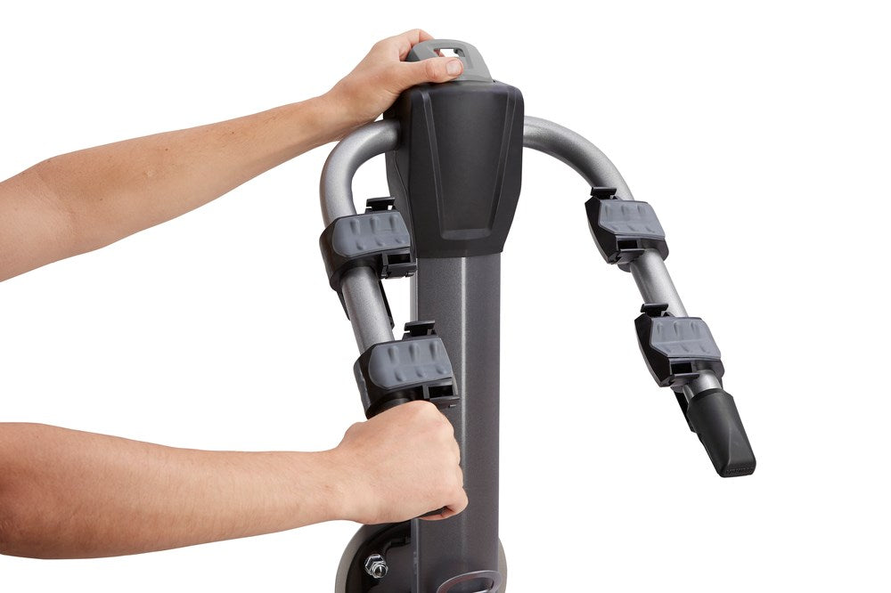 Hands demonstrating Yakima SpareRide hitch bike rack with gray and black components