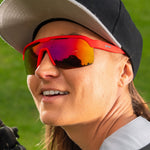 Woman wearing red Goodr sunglasses with orange-red gradient lenses and visor outdoors