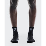 On Performance Run Sock Mid in black worn on model legs against white background