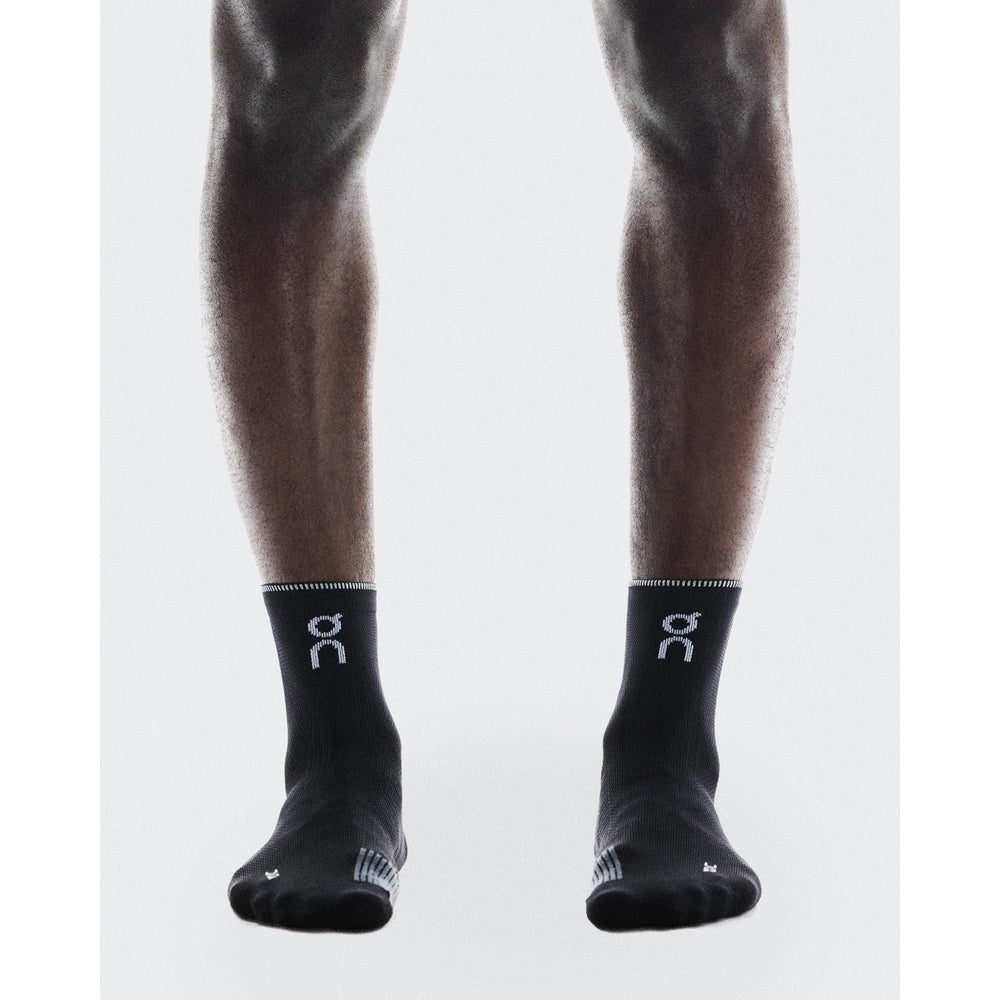 On Performance Run Sock Mid in black worn on model legs against white background