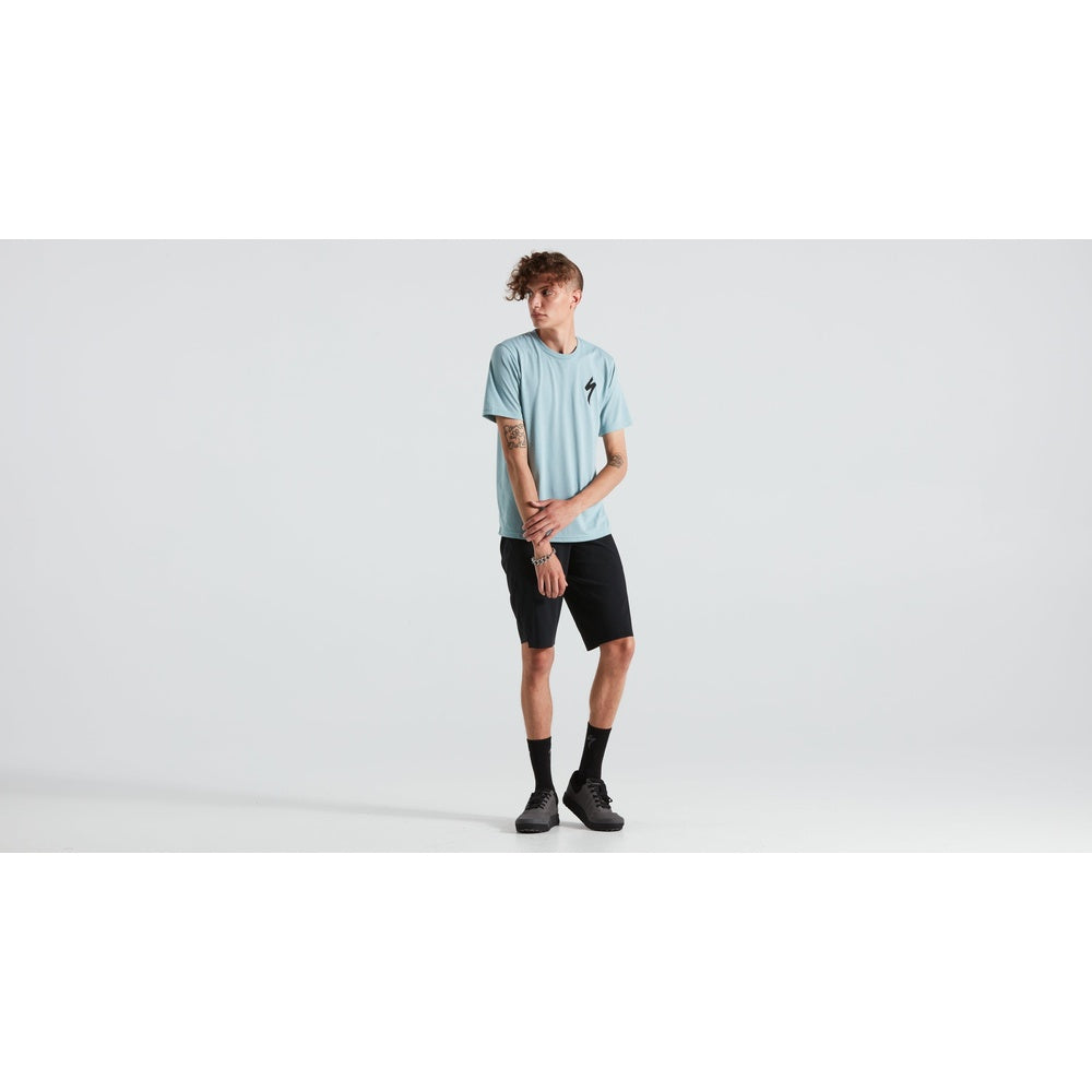 Man wearing light blue Specialized S-logo t-shirt with black shorts in studio setting