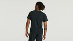 Man wearing dark green Specialized short sleeve t-shirt, back view against white background