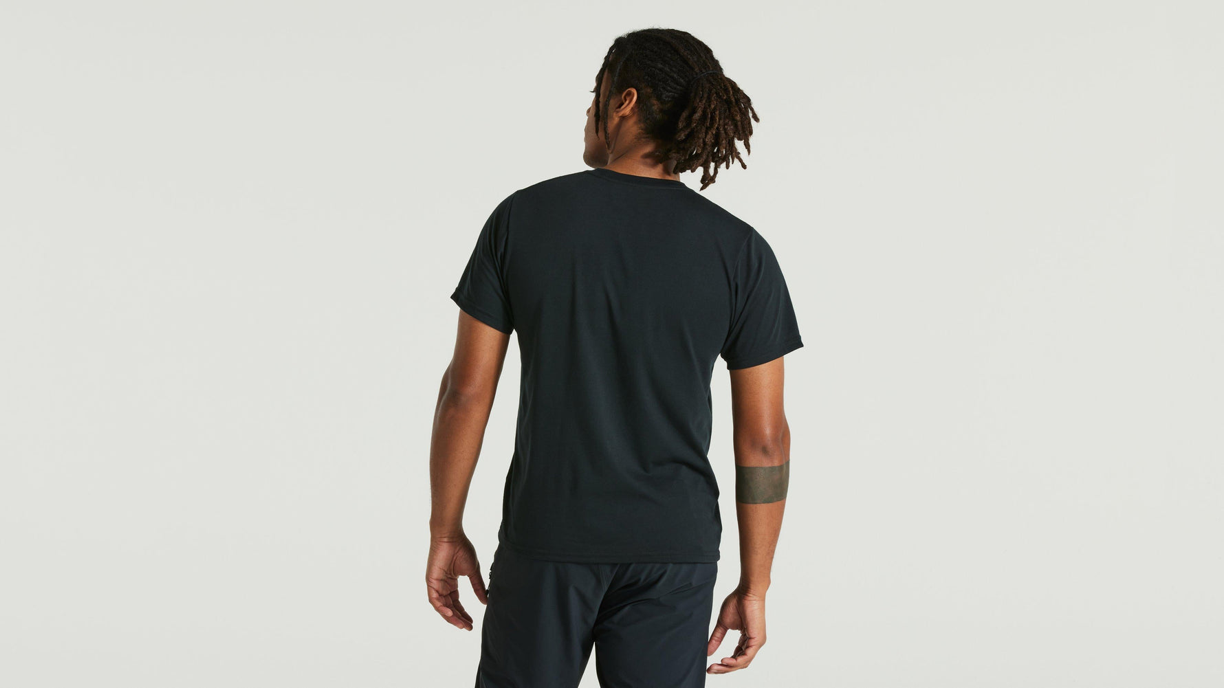 Man wearing dark green Specialized short sleeve t-shirt, back view against white background