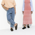 Two people wearing black Birkenstock Boston clogs in professional studio setting