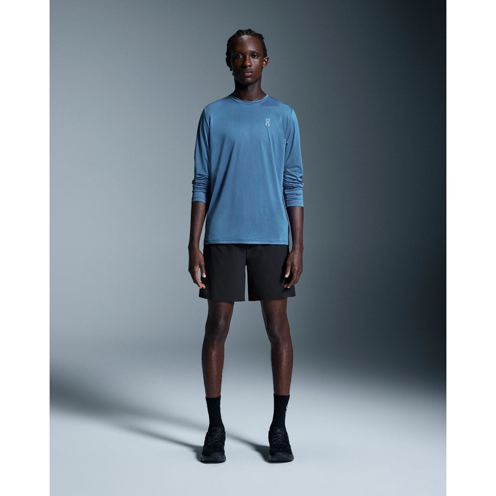 Man wearing black On Running 7-inch performance shorts with blue long-sleeve shirt