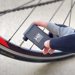 Hand holding black Hi-Line electric tire pump next to bicycle wheel