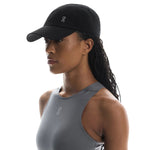 Woman wearing black On Lightweight Cap with perforated design and gray athletic tank top