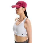 Woman wearing pink On Lightweight Cap with perforated ventilation and white sports bra