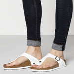 White Birkenstock Gizeh sandals with cork footbed worn with rolled denim jeans
