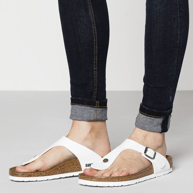 White Birkenstock Gizeh sandals with cork footbed worn with rolled denim jeans