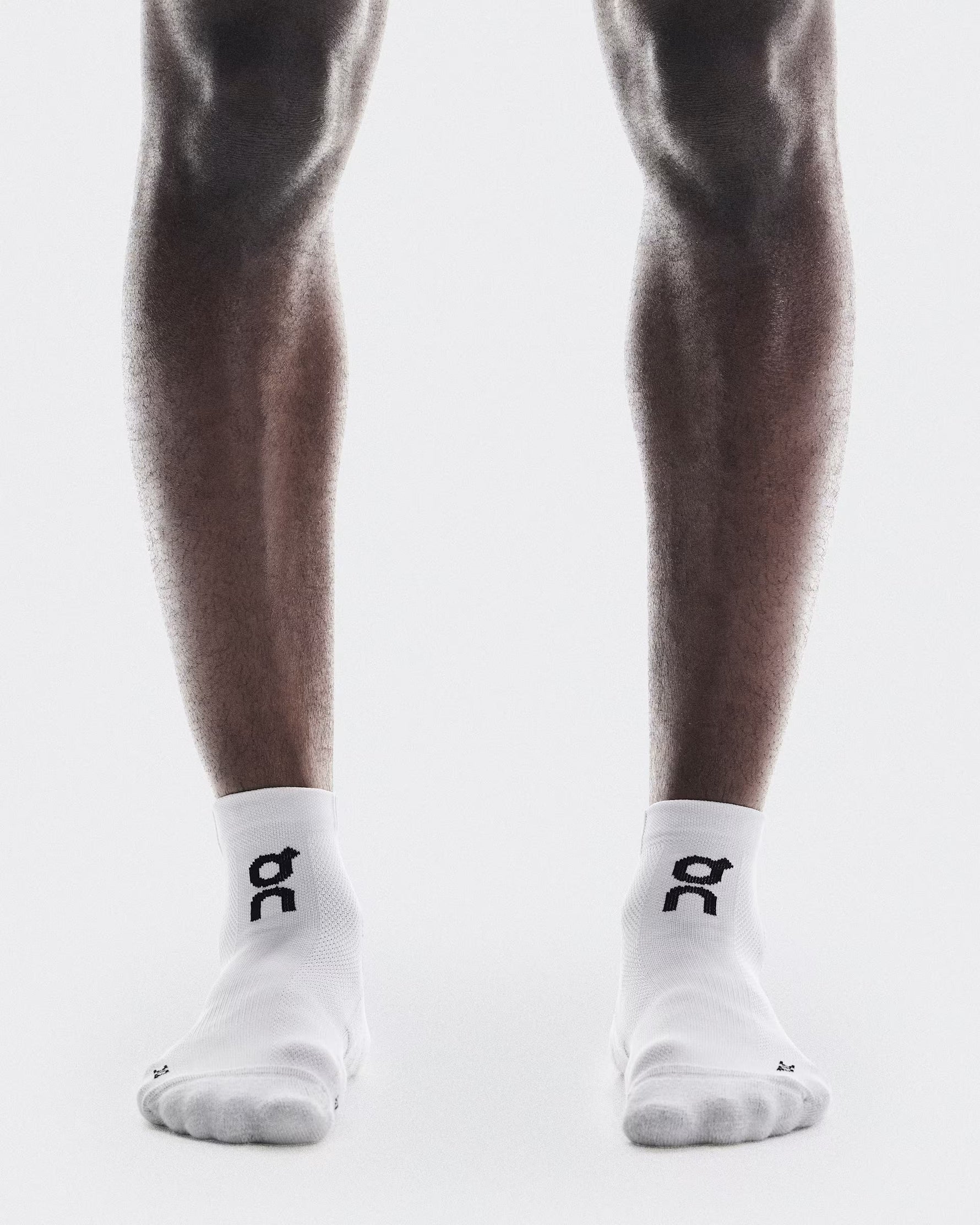 Person wearing white On Core Run Socks with black logo on clean background