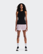 Woman wearing black sleeveless tank top with light pink shorts and white sneakers