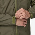Man wearing Patagonia Boulder Fork Rain Jacket in olive green adjusting cuff