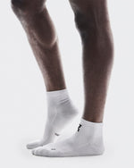 Person wearing white On Core Run mid-height athletic socks with black logo branding