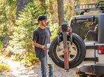 Man using Yakima SpareRide bike rack mounted on Jeep spare tire in outdoor setting