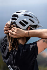 Person wearing white KASK Caipi cycling helmet while adjusting hair