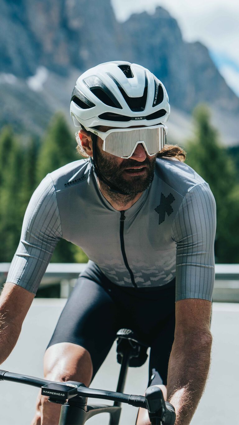 Cyclist wearing white Kask Elemento helmet with aerodynamic design and sunglasses