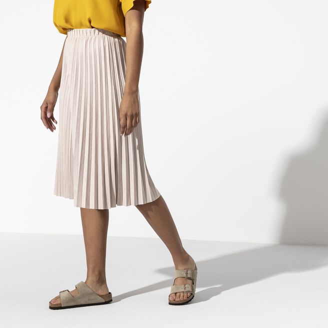 Birkenstock Arizona sandals in taupe suede worn by model with pleated skirt