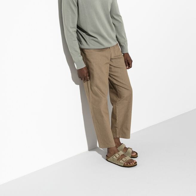 Person wearing taupe Birkenstock Arizona sandals with suede straps in studio setting