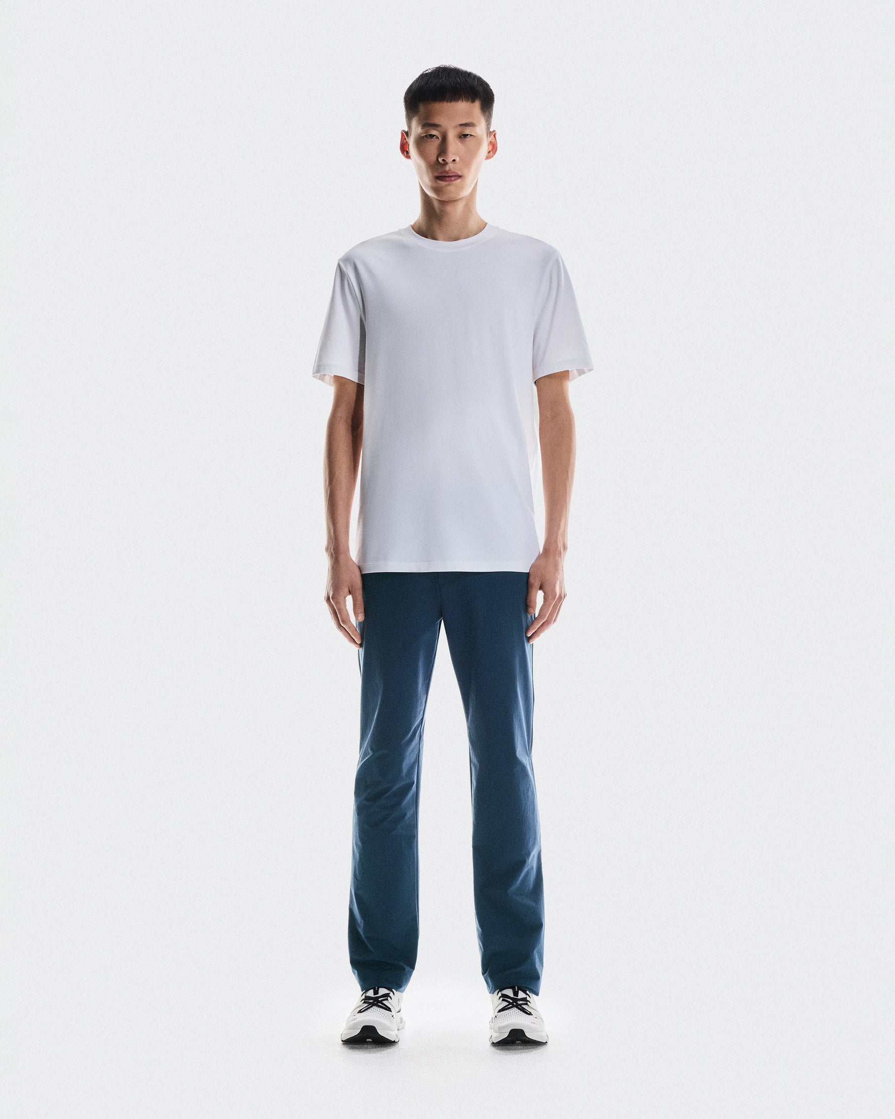 Man wearing white t-shirt and dark blue On All-Day Classic pants with sneakers