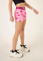 Woman wearing pink heart-patterned compression shorts with matching waistband in studio setting