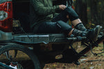 Person wearing black Dakine knee pads while sitting on truck tailgate with mountain bike