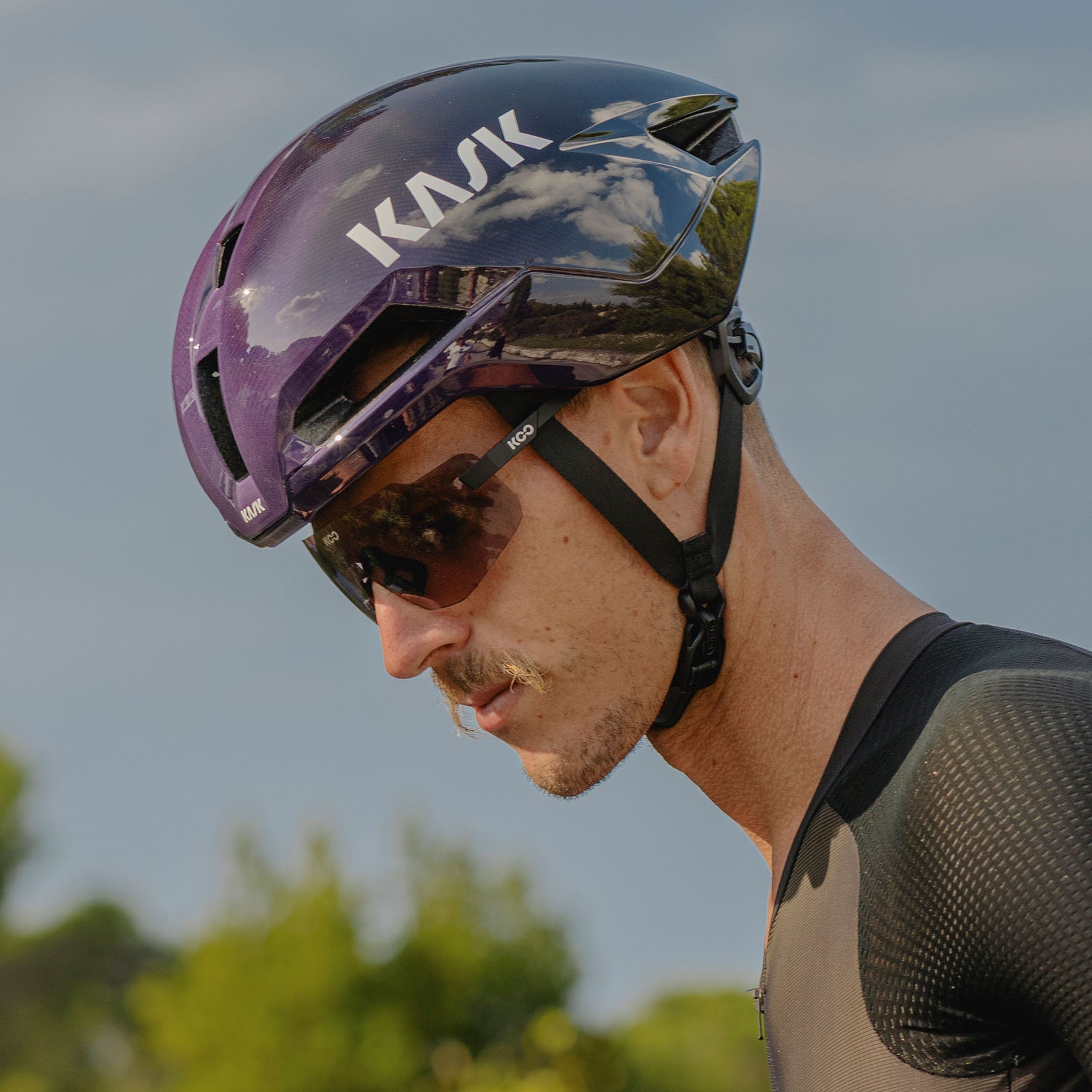 Professional cyclist wearing purple Kask Nirvana helmet with integrated visor during outdoor training