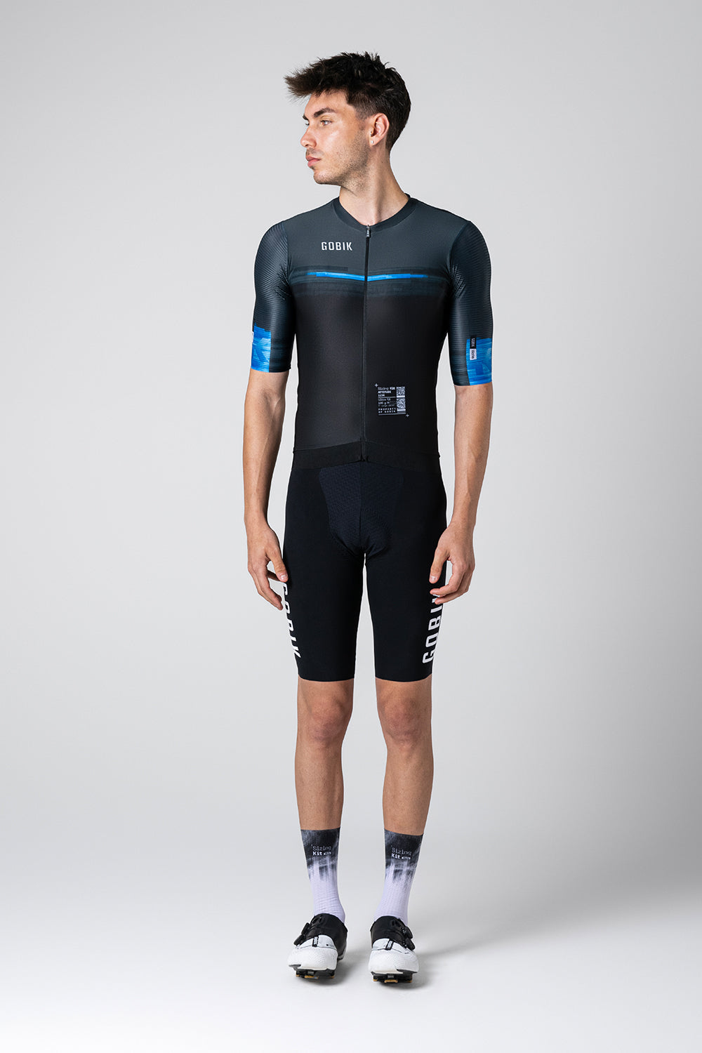 Male model wearing black Gobik cycling skinsuit with blue accents and white socks