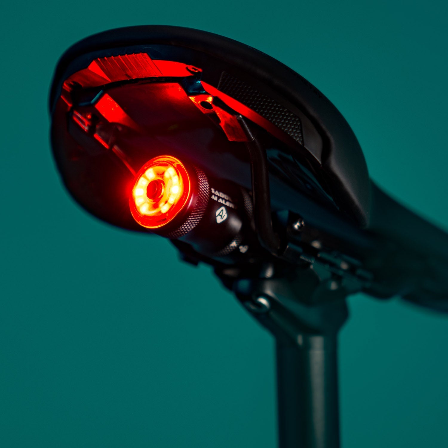 Lezyne black bike rear light with red LED illuminated against teal background