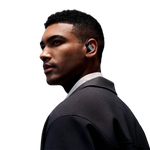 Professional man wearing black Shokz OpenFit Pro wireless earbuds in studio portrait