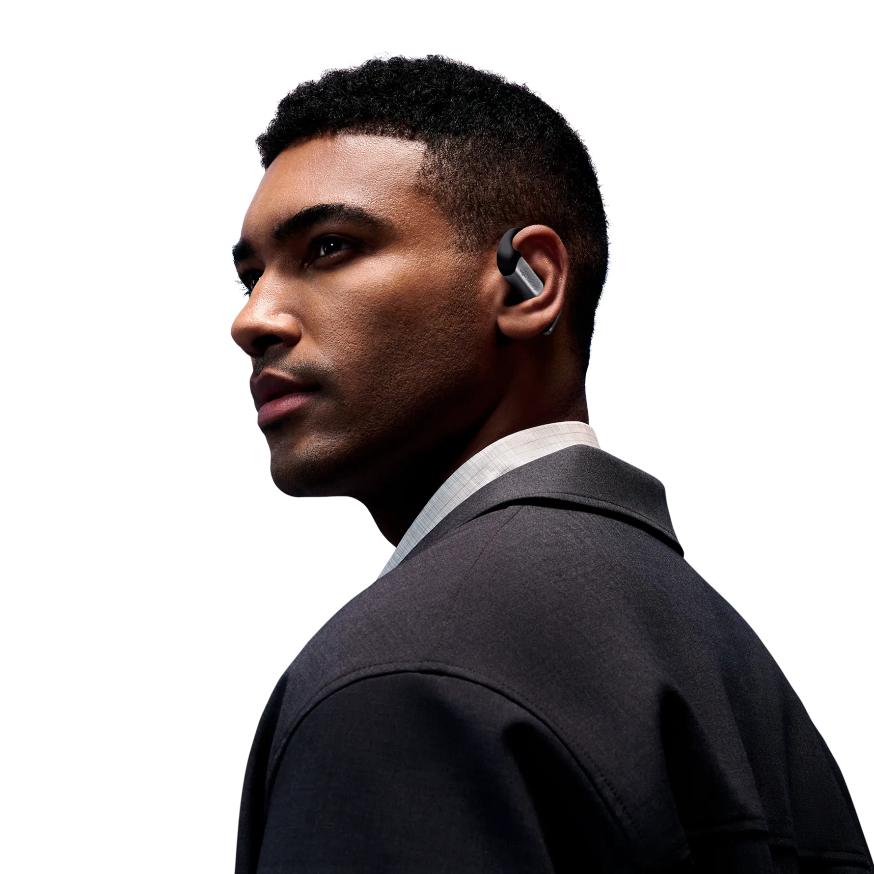 Professional man wearing black Shokz OpenFit Pro wireless earbuds in studio portrait