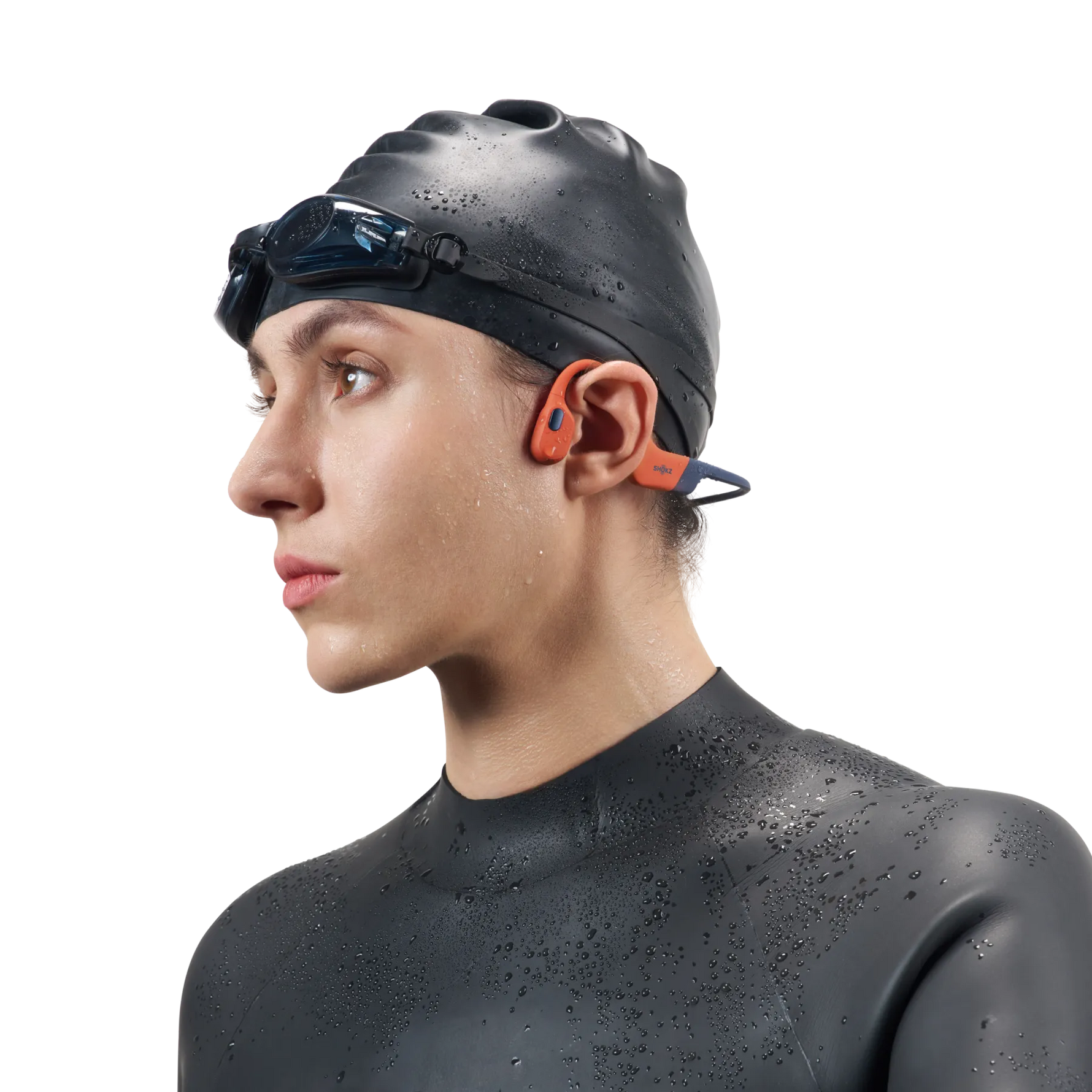 Person wearing orange Shokz bone conduction headphones with swim cap and goggles