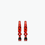 Pair of red Muc-Off Big Bore Lite tubeless Presta valves on white background