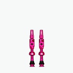 Two bright pink Muc-Off Big Bore Lite Tubeless Presta Valves on white background