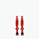 Two red Muc-Off Big Bore Lite tubeless Presta valves on white background