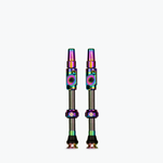 Two Muc-Off tubeless presta valves with rainbow iridescent finish on white background