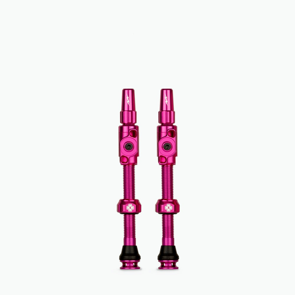 Two pink Muc-Off Big Bore Lite tubeless Presta valves on white background
