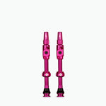 Two pink Muc-Off Big Bore Lite tubeless Presta valves on white background